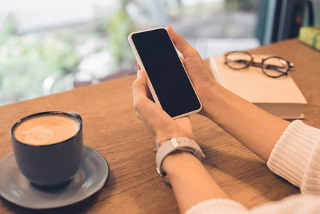 桌子局部在咖啡馆的桌子上,女人在智能手机上拍咖啡杯的照片照片