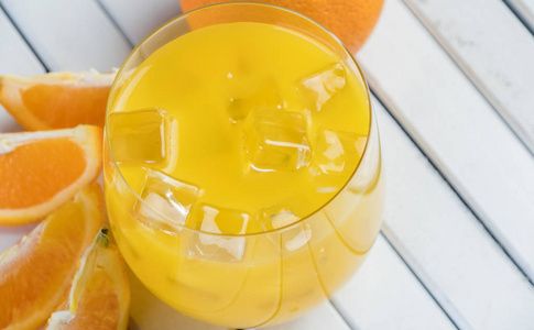 木制桌子上的冷鲜橙汁和水果。