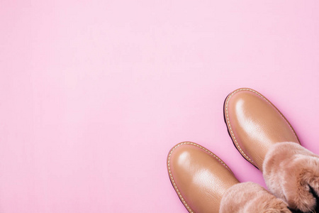 s warm shoes with fur on light pink background. Concept of the N