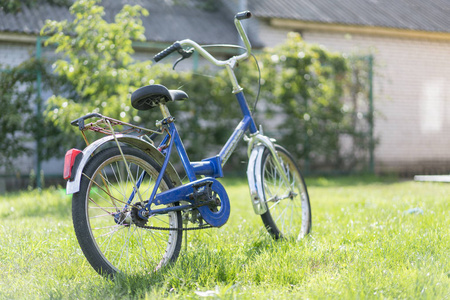 s bicycle on the grass. Blue teen bike on a green lawn in the ya