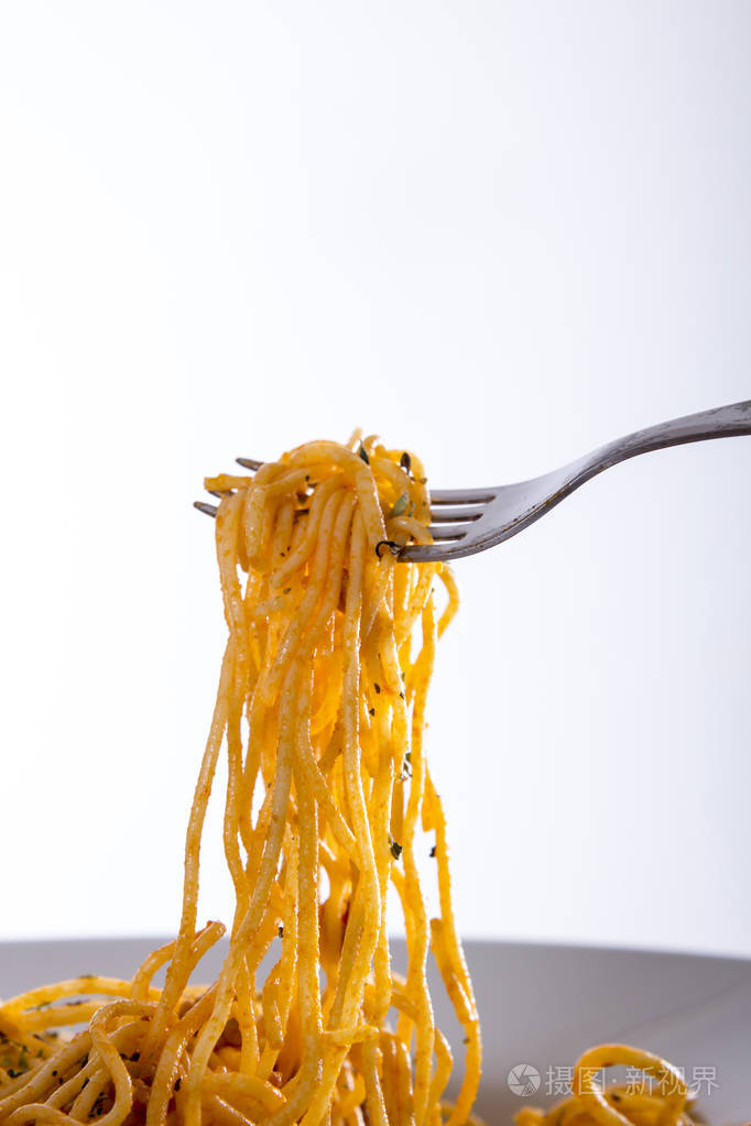 白色背景下叉子上的煮熟意大利面