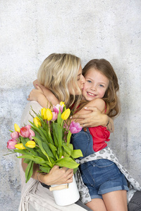 小可爱的女儿用一束五颜六色的鲜花祝贺年轻的母亲，母亲节的概念