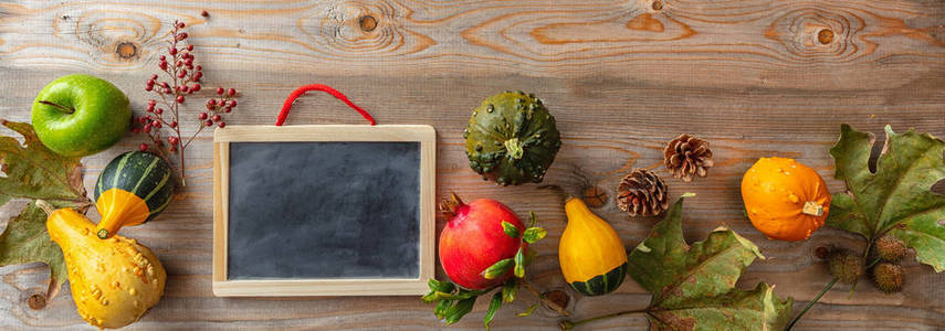 感恩节的概念。五颜六色的南瓜，水果和空白黑板上的乡村木制背景，复制空间，横幅