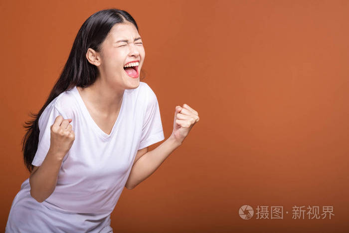 年轻的亚洲时髦女人穿着白色t恤,大赢尖叫姿势两只手举起.