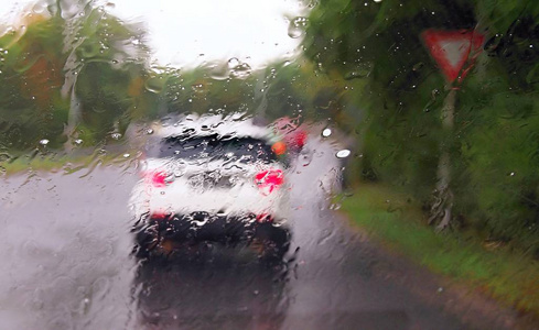 在大雨和暴风雨中驾驶一辆汽车。 在驾驶汽车时，通过挡风玻璃观看雨滴。 浅场深。