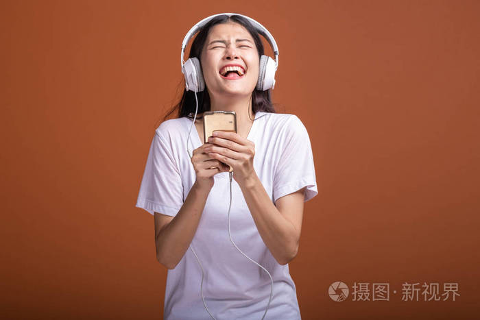 年轻的亚洲女人带着手机听音乐,心情很开心. 时尚生活方式概念