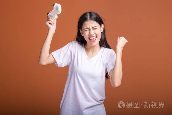 女性玩家被隔离在橙色背景上年轻的亚洲时髦女人拿着控制台游戏操纵杆