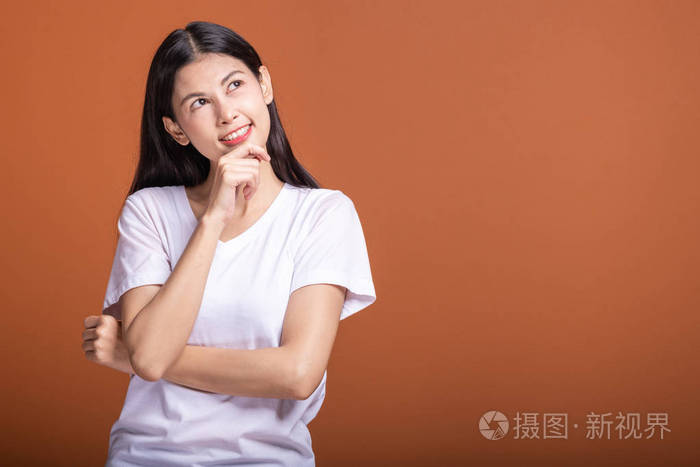 年轻的亚洲时髦女人穿着白色t恤,下巴上有思考的姿势手指.