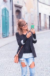 可爱的女人在城市环境中拿着手机。