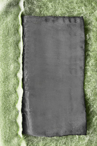 绿色纺织品背景特写上的黑色空白纺织服装标签