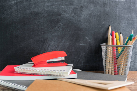 侧面看一张木制桌子，上面有学校用品。 带彩色铅笔的水桶，笔记本，尺子，步进器。 回到学校的概念
