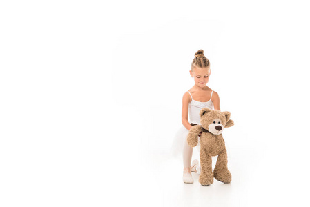 快乐的小芭蕾舞演员，穿着图图，坐着泰迪熊，白色背景被隔离