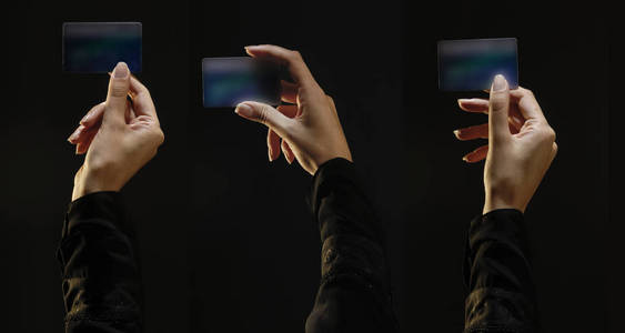 三只手握着信用卡的女性手,上面有黑色背景照片