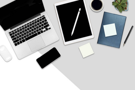 办公桌的平躺照片，配有笔记本电脑数字平板手机和配件。 现代两种色调白色和灰色背景。 桌面办公室模型概念。