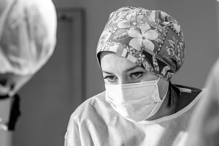 女外科医生在手术中戴着防护面具和帽子.