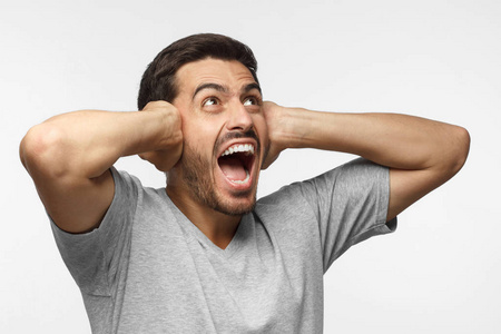 年轻人对吵闹的邻居大声喊叫,用双手捂住耳朵照片