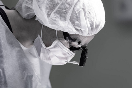 女外科医生在手术中戴着防护面具和帽子。医疗保健医学教育急救医疗手术理念