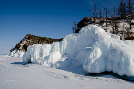 贝加尔湖被冰雪覆盖，强烈的寒冷，厚厚的清澈的蓝色冰。冰柱挂在岩石上。贝加尔湖是一个寒冷的冬天。令人惊叹的地方，遗产，美丽的俄罗斯