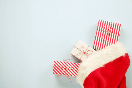 圣诞老人的帽子和新年礼物包裹在节日的五颜六色的工艺纸和丝绸蝴蝶结安排在节日的组成。关闭背景，复制空间，顶部视图。寒假准备概念