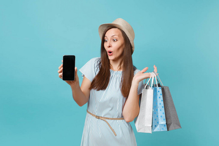 夏天穿着草帽的女人的肖像，手里拿着包袋，购物后买了手机，手机上的空屏幕被隔离在蓝色的彩色背景上。 广告复制空间