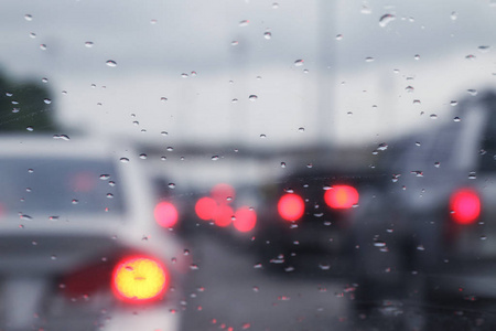 背景模糊的交通堵塞和雨水滴在玻璃上，带有Bokeh照明车