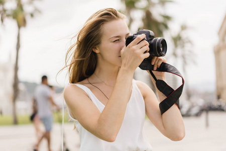 专业的女摄影师在公园里用现代的dslr相机拍照,同时在新鲜空气中漫步
