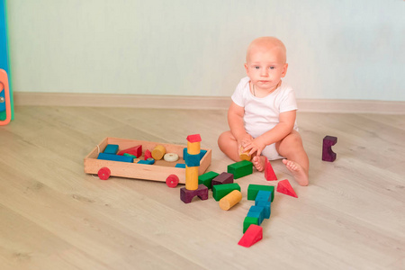 可爱的小婴儿在房间里玩彩色木块。 早期发展概念