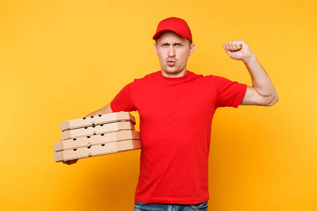送货员穿着红色帽子T恤，在黄色背景上隔离了食品订单披萨盒。 男员工皮萨曼或快递员制服持有意大利披萨在纸板平板盒。 服务概念