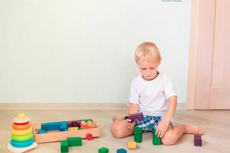 可爱的小男孩在房间里玩彩色木块。 早期发展概念