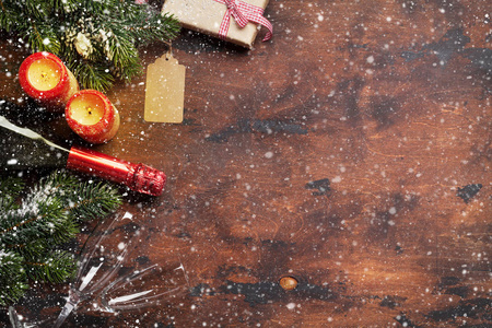 圣诞礼盒，蜡烛，香槟，杉树枝，覆盖着雪在木制背景上。 顶景圣诞背景，您的问候空间