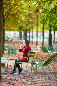 美丽的年轻女子在巴黎的杜勒里花园，在一个明亮的秋天，用她的手机自拍。 法国秋季旅游和度假