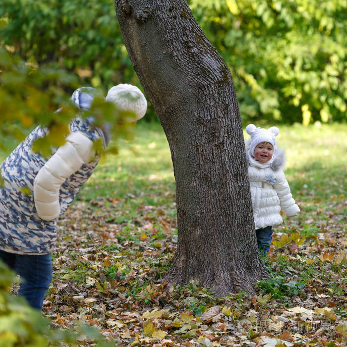 小女孩和她妈妈在公园的草地上玩捉迷藏