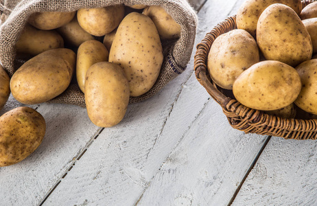 熟土豆放在麻布袋和木篮里，自由地躺在木板上。