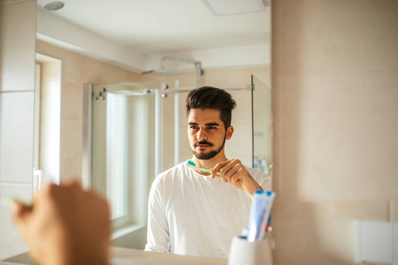 英俊的年轻人在浴室刷牙的肖像。