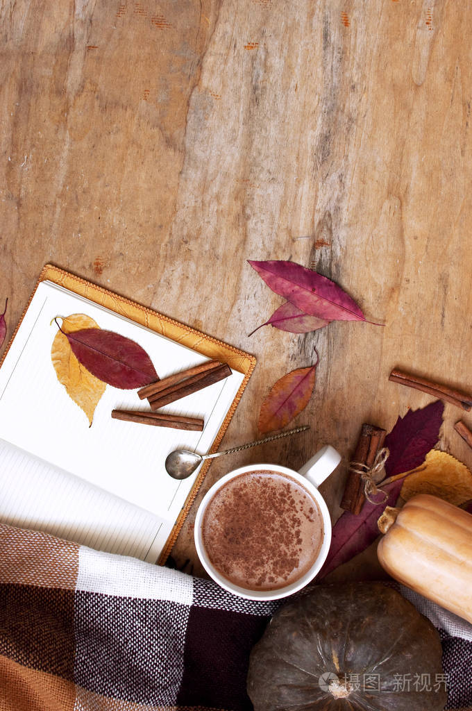 乡村木制背景南瓜和秋天留下一杯南瓜拿铁与咖啡或可可，一个笔记本，一个格子在笼顶视图。 秋天的背景。