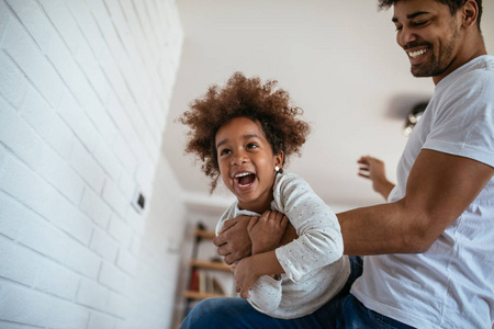 拍摄非裔美国人父亲和女儿在家一起玩得很开心。