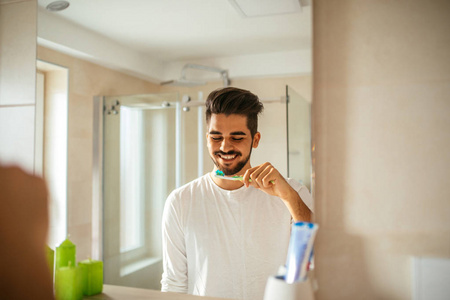 英俊的年轻人在浴室刷牙的肖像。