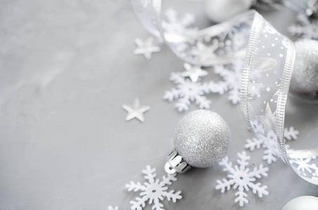 银色圣诞背景。 带有装饰球和雪花的卷曲丝带。 圣诞装饰品。 复制空间。
