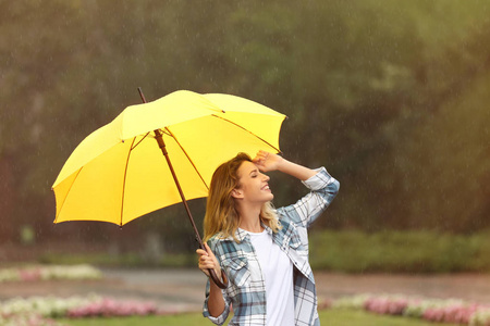 公园里下雨的带伞的快乐年轻女子