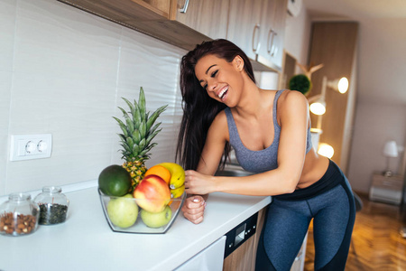 一位微笑的运动员女士伸手寻找健康食物的肖像。