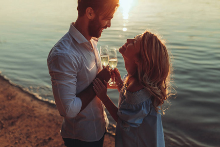 日落时品尝葡萄酒的年轻夫妇的肖像。