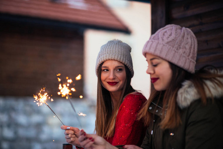 两个年轻女人在户外用闪闪发光的棍子庆祝的照片。