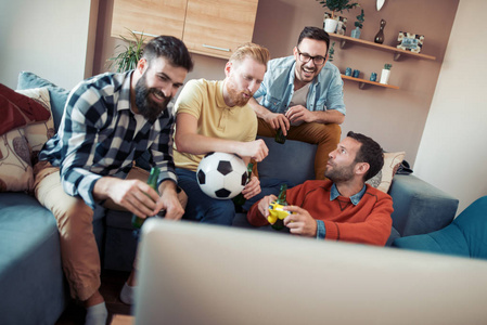 快乐的男性朋友在家玩，在电视上看足球