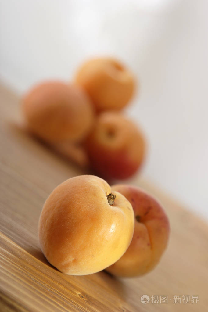木桌上放着一堆新鲜成熟的杏子