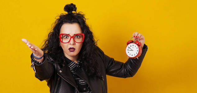 兴奋的年轻时髦女孩拿着闹钟隔离在黄色背景上. 复制空间.