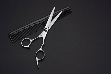 黑色背景的理发师剪刀和梳子照片