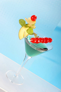 马提尼杯蓝色鸡尾酒，樱桃和水果装饰接近