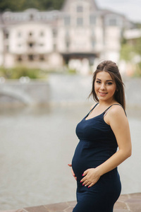 美丽的年轻开朗的孕妇站在喷泉背景