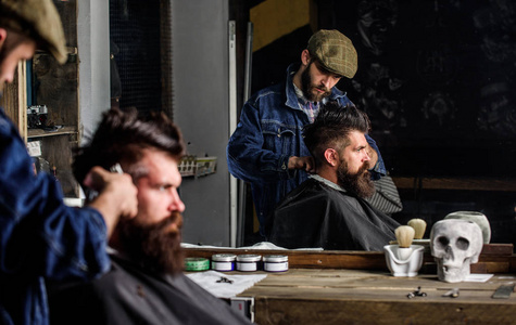 理发师与理发剪工作的发型胡子男子理发店背景。时髦的生活方式概念。时髦的客户得到理发。理发师的发型野蛮胡子客户端与剪刀