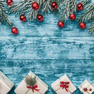 圣诞节蓝色背景与手工礼物和冷杉枝与红色球体。 文本空间。 上面的风景。